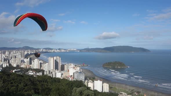 Paraglider with colourful wing canopy flies low past launch site