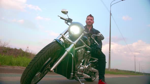 Young Man Sitting on Motorcycle on the Road at Sunset Slow Motion