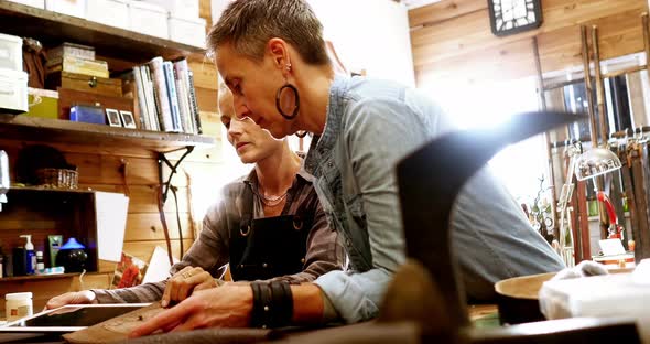 Craftswomen preparing leather cover for digital tablet