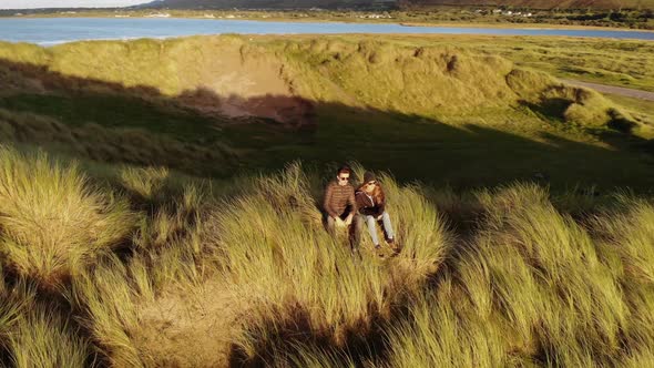 Flight Around a Couple Sitting on the Dunes at the Irish West Coast