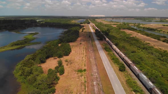 Aerial Of Railroad With A Cargo Train , Country Road And Lakes