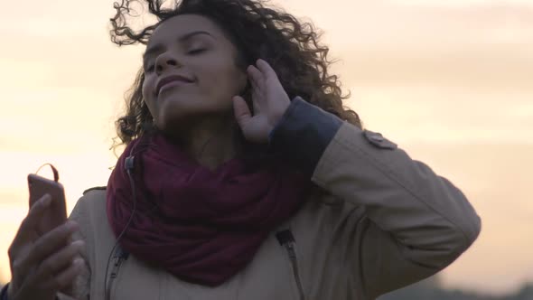 Attractive Mixed Race Woman Listening to Music, Dancing in Trance at Sunset