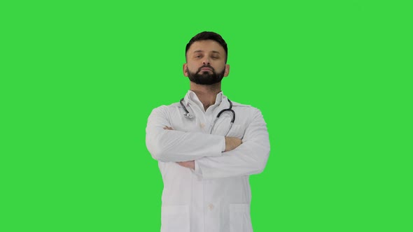 Young Male Caucasian Doctor Standing with Folded Hands on a Green Screen, Chroma Key