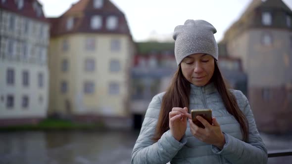 Woman Is Reading Sms and Watching Pictures in Smartphone in Autumn in City