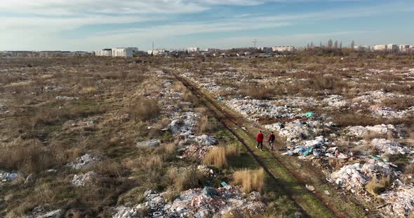 Two People Walking on a Huge Aste Garbade Dump Rubbish Landill in Bucharest