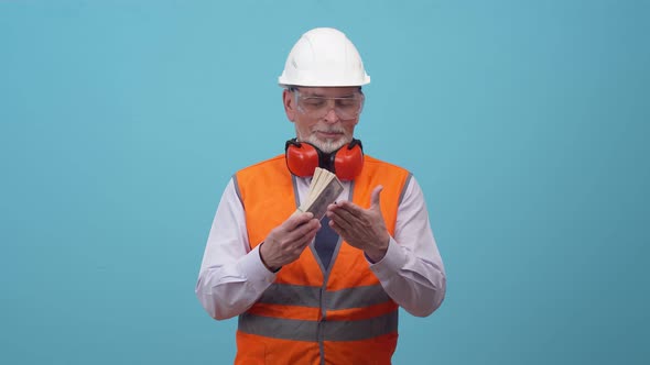 Adult engineer is man in a work vest and helmet slams bundle of dollars on hand