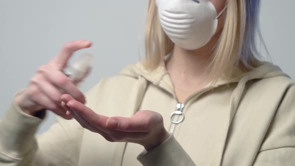 Blonde woman in protective mask with disinfection gel