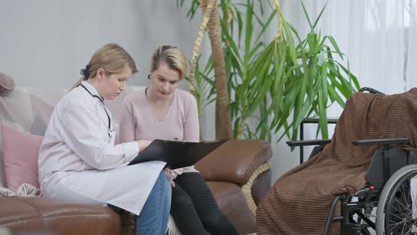 Professional Doctor or Nurse Showing Bad Examination Results To Sad Paraplegic Woman