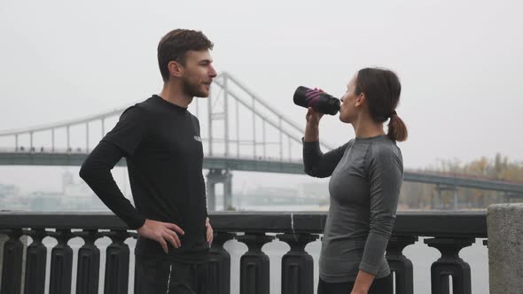 Happy Sportive Active Couple in Sportswear Resting & Relaxing After Running Training Drinking Water