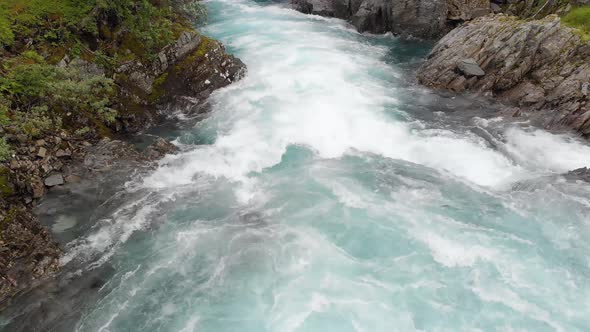 Strong river whitewater rapids flowing down mountainside, aerial reveal