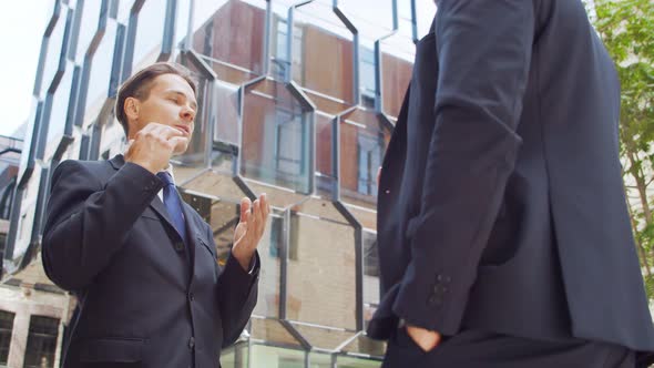 Confident businessman and his colleague in front of modern office building.