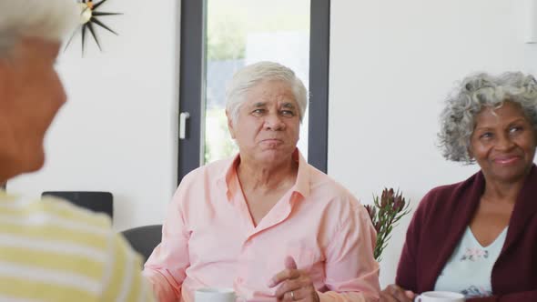 Happy senior diverse people drinking tea and talking at retirement home