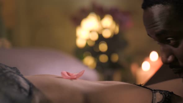 Man Blowing Rose Petals on Woman's Body