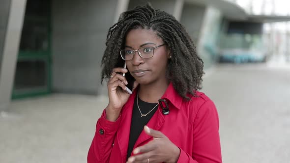 Afro-american Woman Talking on Phone Outside, Looking Serious