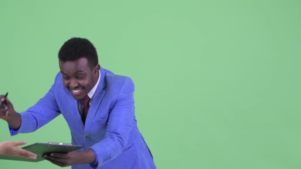 Happy Young African Businessman Writing on Clipboard