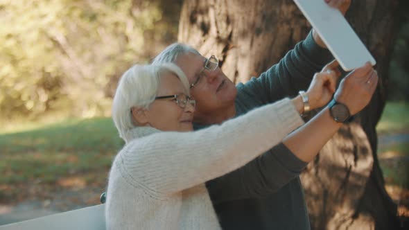 Happy Senior Couple Talking with Their Grandkids Via Tablet