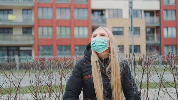 Blonde Girl in a Medical Mask Sitting on the Bench.