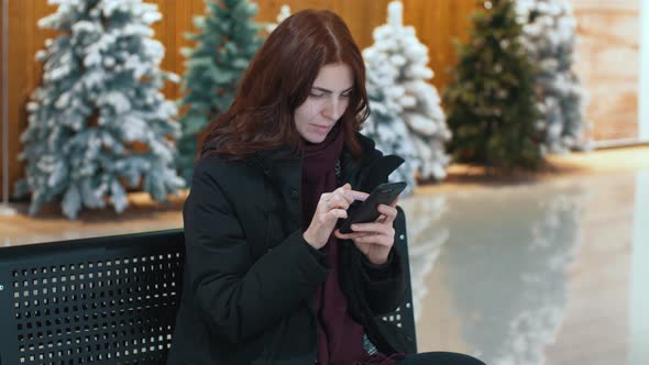 A Young Beautiful Woman in the Christmas Store Use Smart Phone