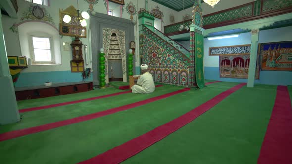 Muslim Mosque Teacher is reading the Quran in Small Historic Wooden Masjid