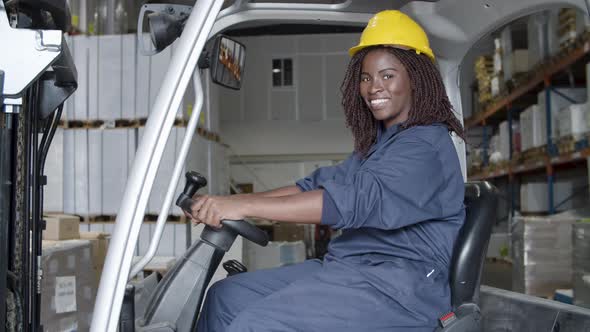 Happy African American Female Worker Sitting in Forkfit