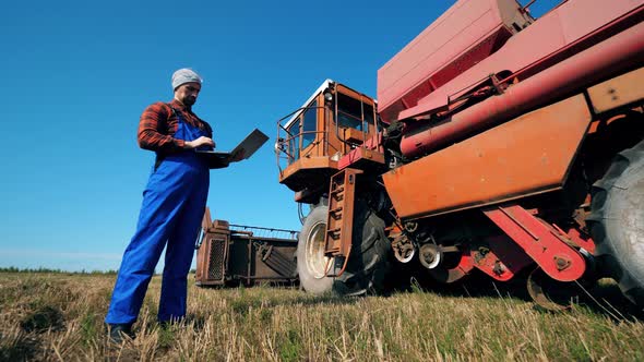 Cultivator, Professional Agrarian, Farmer with a Laptop Is Looking at the Combine