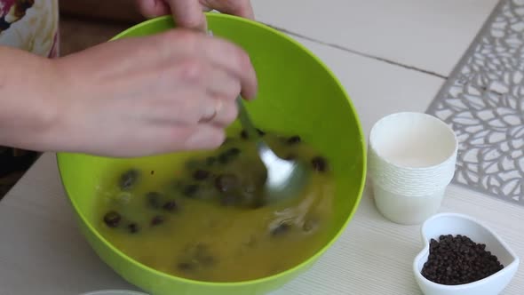 A Woman Prepares Muffins With Chocolate And Raisins.