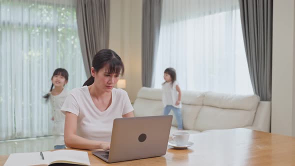 Asian business woman mother work from home with children playing aroun, loss concentrate on job. alt