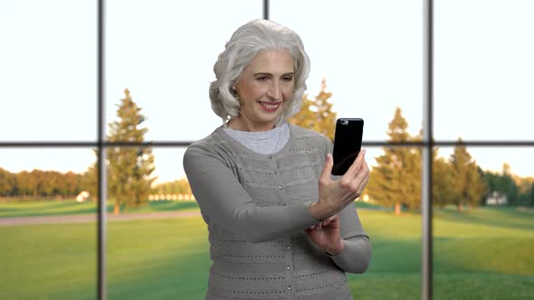 Smiling Mature Woman Taking Picture on Her Smartphone.