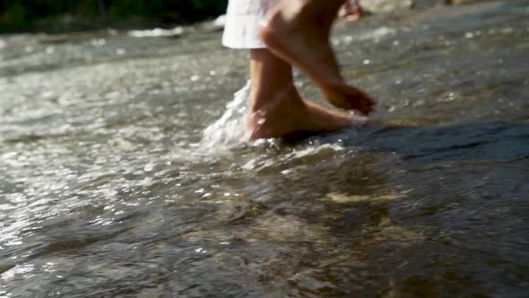 Slow motion of feet walking through the water in a river.