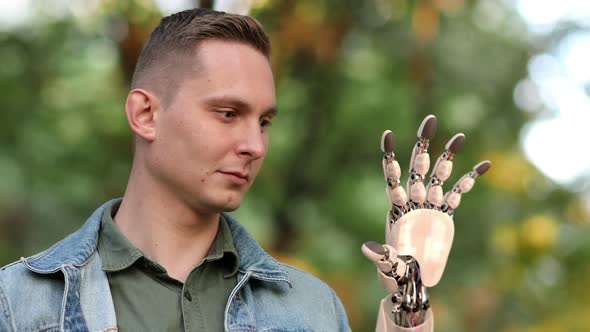 Young Man Looks on His Robotic Hand