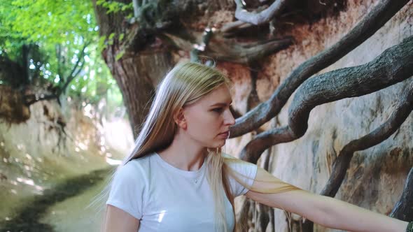 Young Blonde Woman Looking on Exposed Tree Roots in Natural Loess Ravine