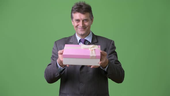 Mature Handsome Businessman Against Green Background