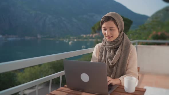 Arab Young Muslim Woman in Hijab Sits Balcony Using Laptop Middle Eastern Female Working Remote From
