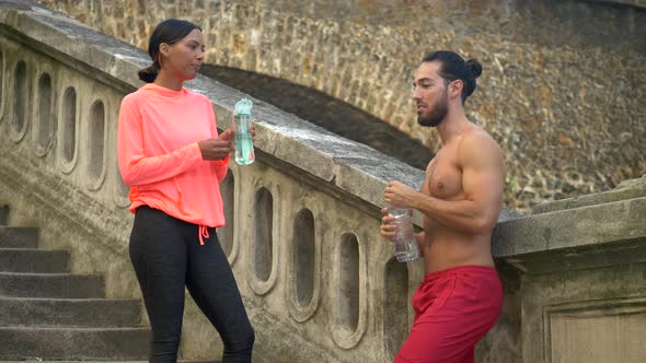 A couple take a break after a workout to drink water