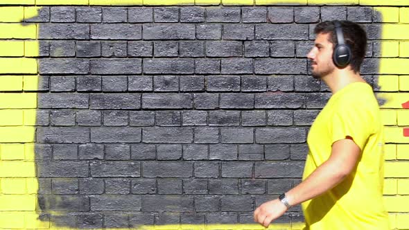 Slow motion shot of man with headphones walking in front of wall