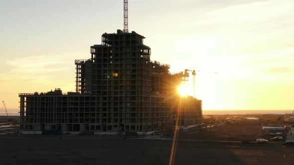 Shooting From a Drone Under Construction Residential Building with Construction Cranes at Sunset