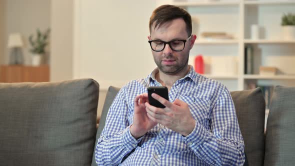 Serious Young Man Using Smartphone at Home 