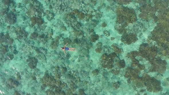 Aerial: woman snorkeling on coral reef tropical caribbean sea turquoise water In