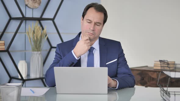 Pensive Businessman Thinking  and Working on Laptop