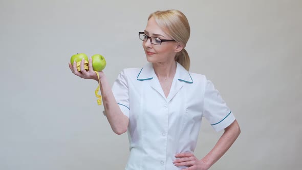 Nutritionist Doctor Healthy Lifestyle Concept - Holding Two Organic Green Apples and Measuring Tape