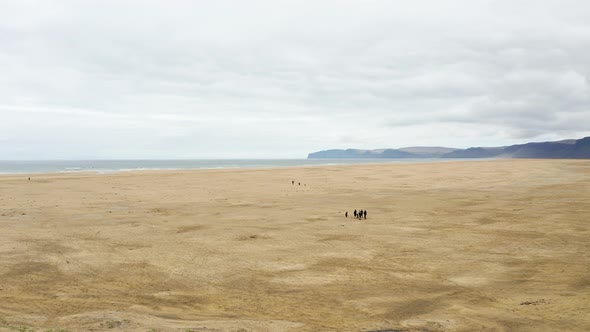 Travelers Walking In The Vast Sand Dunes Landscape Towards The Beach In Iceland