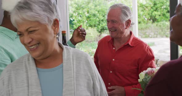 Happy group of diverse senior friends welcoming in doorway at christmas time