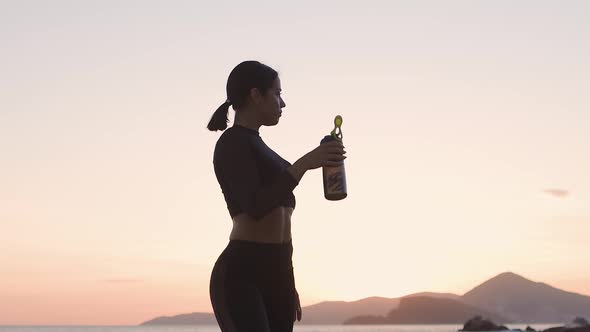 Sporty Sexy Woman Drinking Water on Beach at Sunset