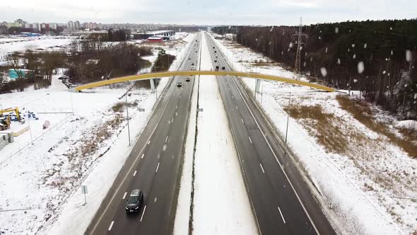 Highway road during heavy snowfall on bright winter day, aerial view