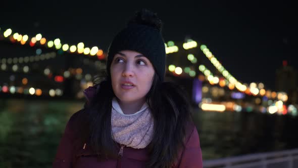 Young Woman Sits at Brooklyn Bridge New York By Night