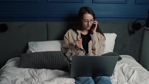 A Woman Talking To Someone on the Phone While Working with a Laptop From Home. Slow Motion