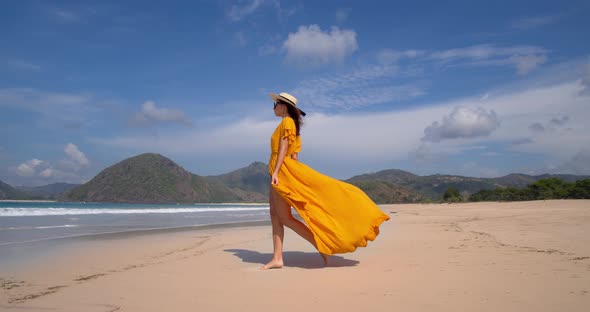 Young Pretty Model in Yellow Dress and Straw Hat Walking Near Ocean Wonderfuul Picture with White