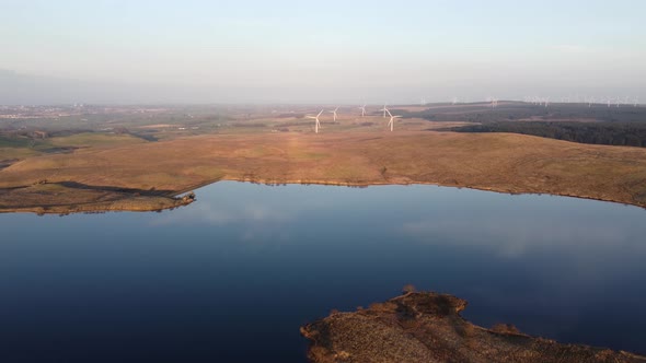 Aerial approach of distant wind turbine farm in rural area of Scotland