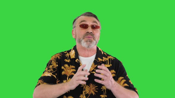 Old Cool Senior Man in Casual Talking To Camera While Walking on a Green Screen Chroma Key