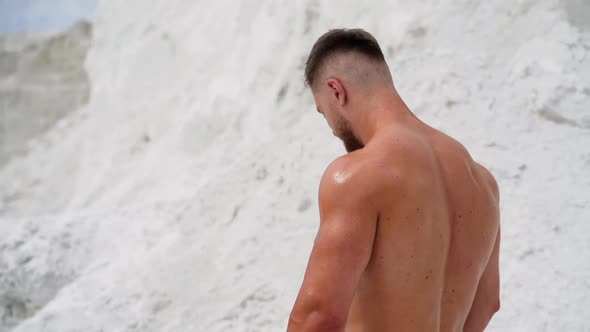 Athletic male resting after work out on nature. Outdoor lifestyle portrait of bodybuilder on natural